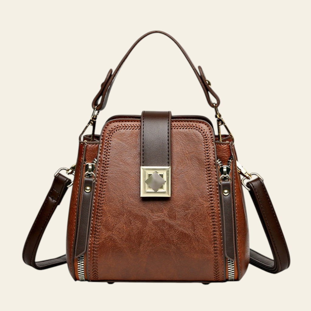 Brown leather handbag with gold accents on a white background