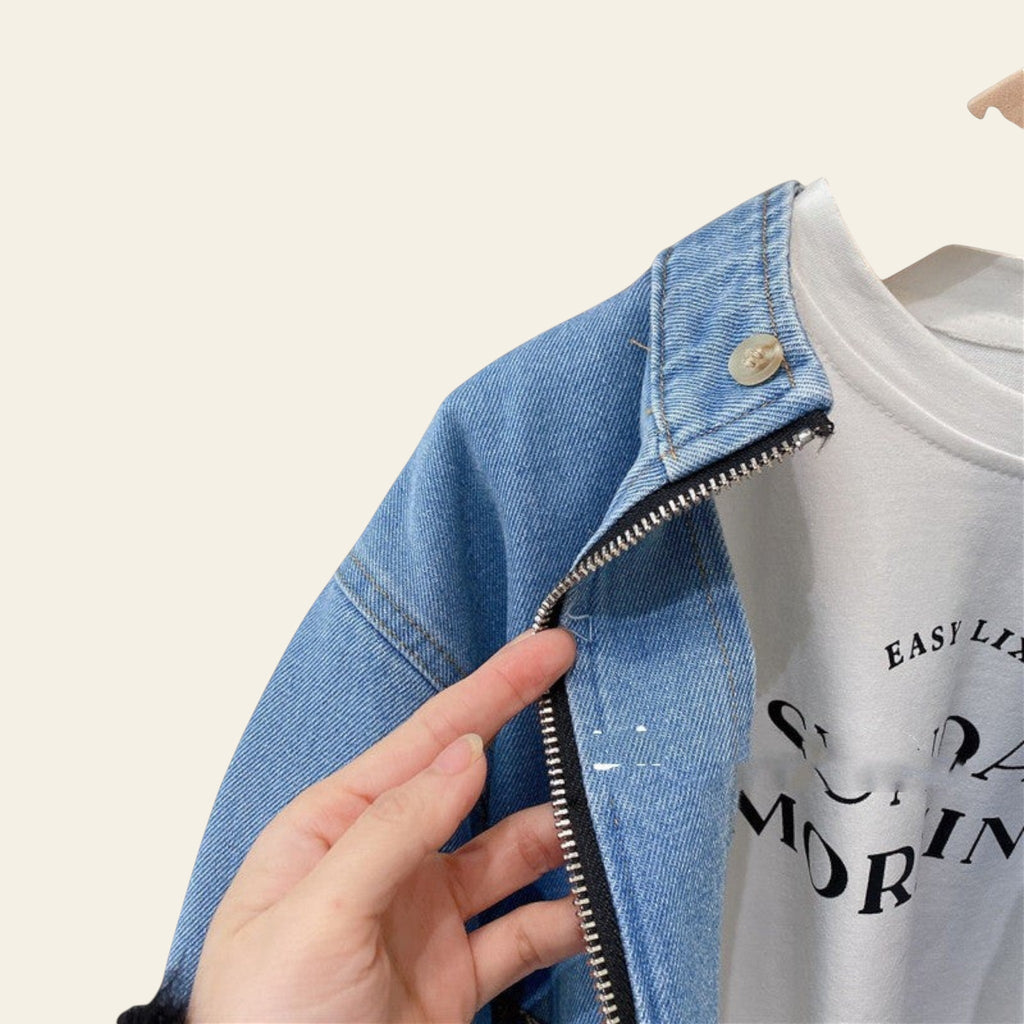 Close-up of a denim jacket with a hand zipping it, with a white t-shirt and green shorts in the background.