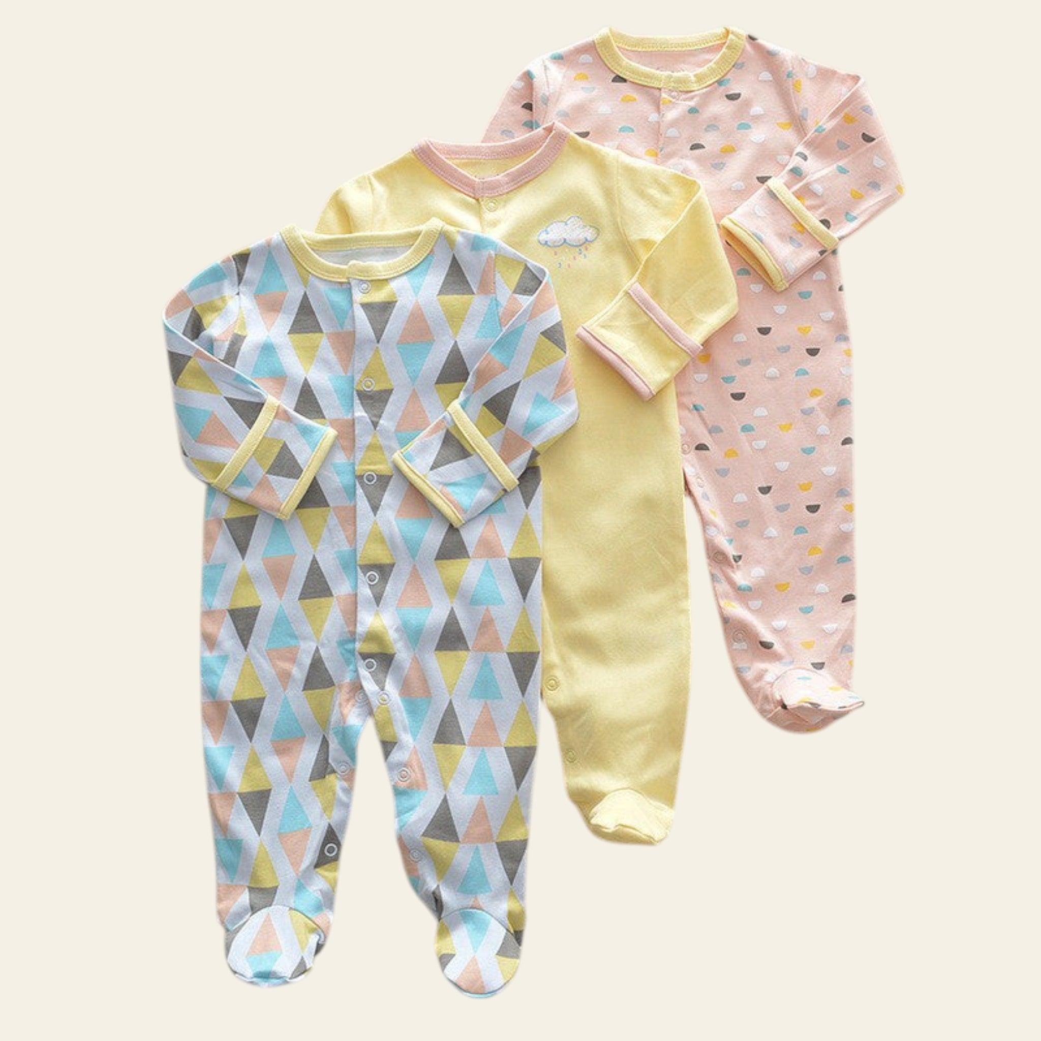 Three baby onesies with different patterns on a beige surface