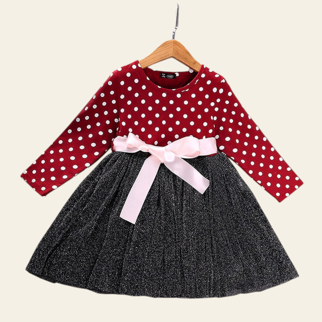 Red polka dot top and black skirt with a pink bow on a wooden surface.