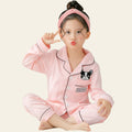 Child wearing pink pajamas with a dog design, sitting on a bed.