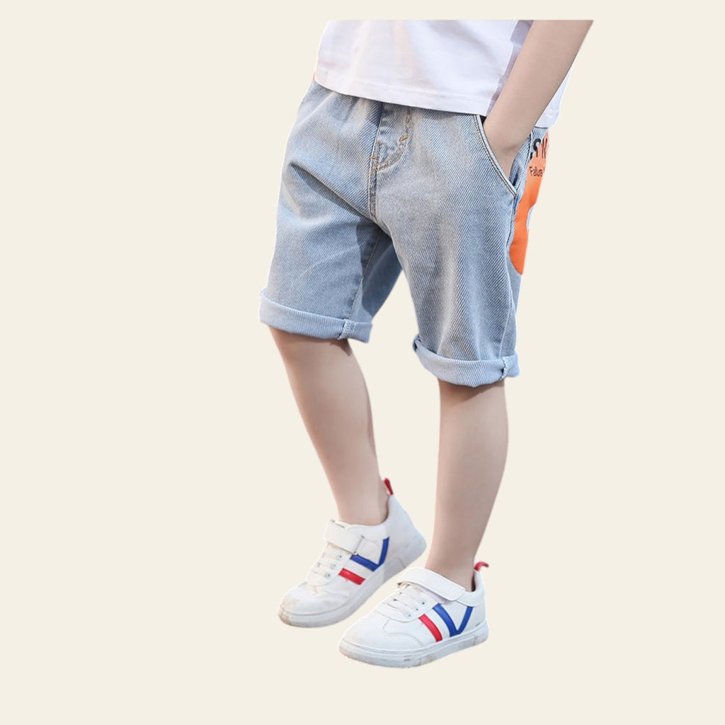 Child wearing light blue denim shorts and white sneakers on a road.