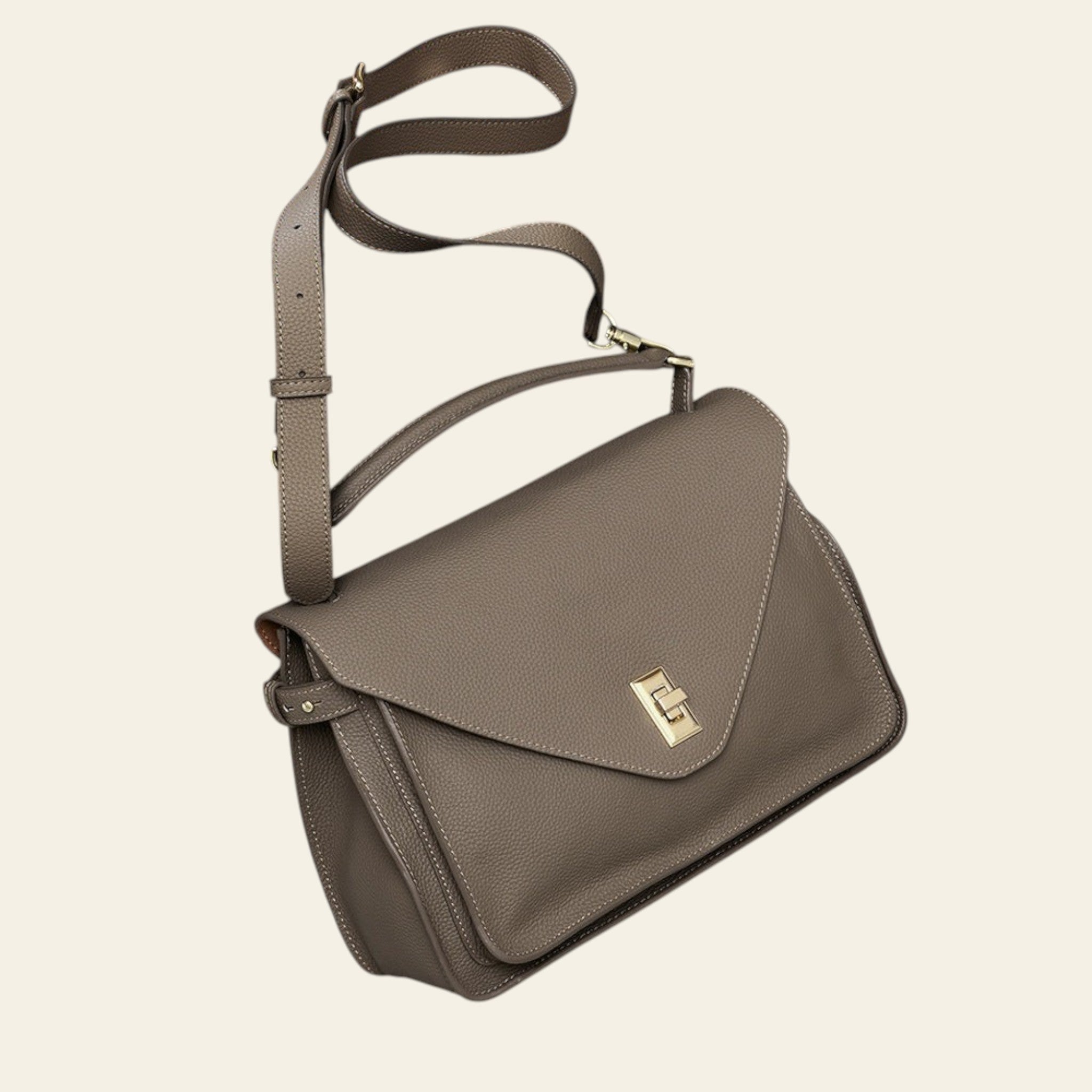 Brown leather handbag with a gold clasp on a light gray surface.
