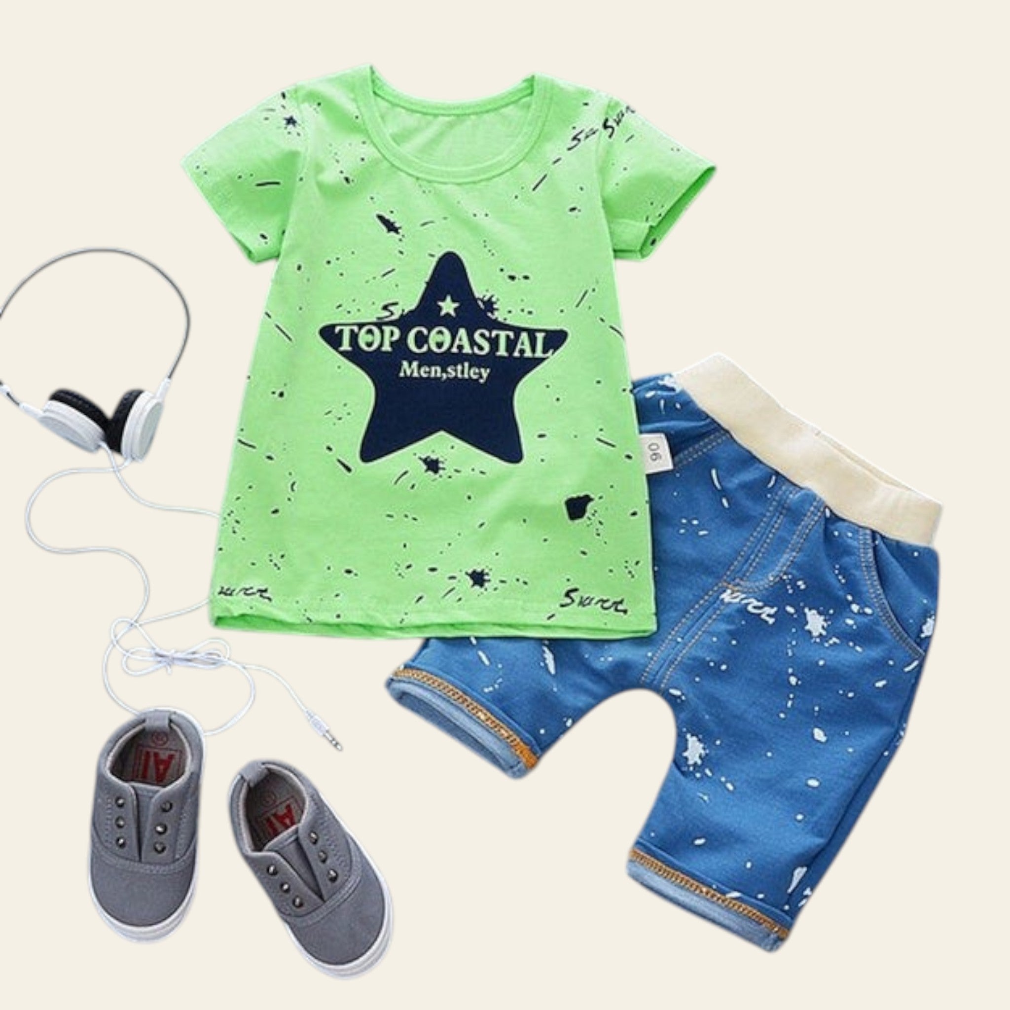 Children's outfit with green t-shirt, blue shorts, and gray shoes on a light blue background.