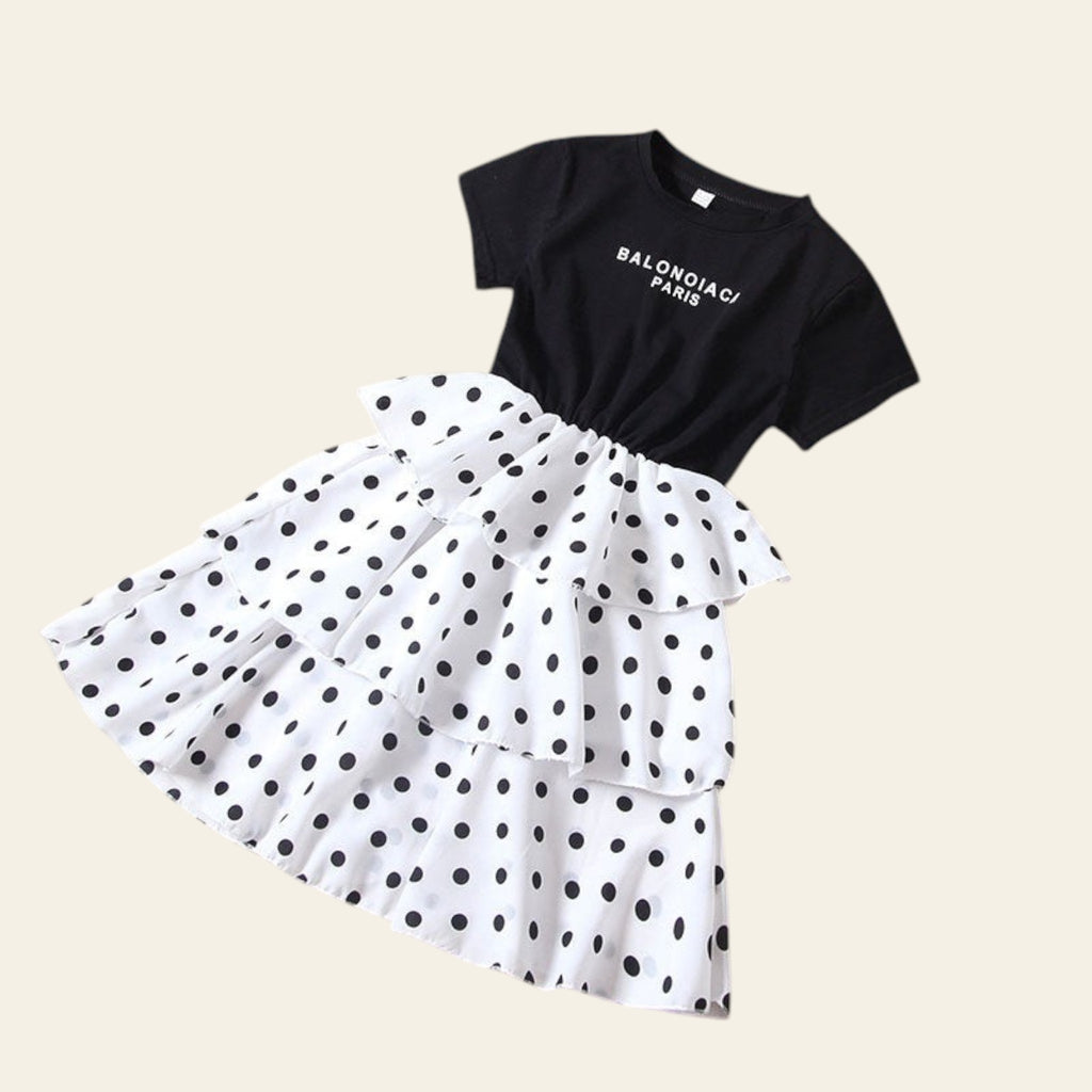Black t-shirt with white polka dot skirt on a beige background
