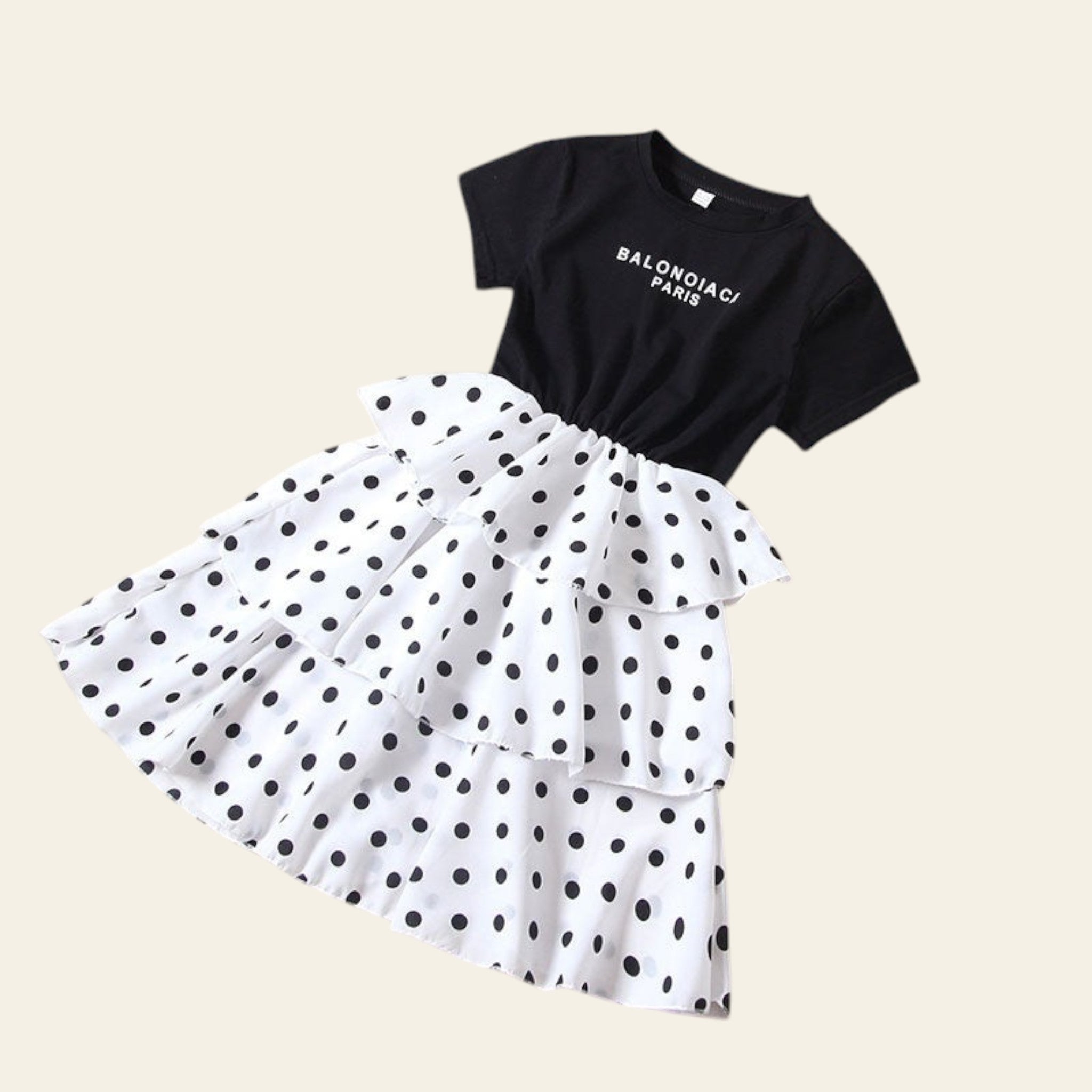 Black t-shirt with white polka dot skirt on a beige background