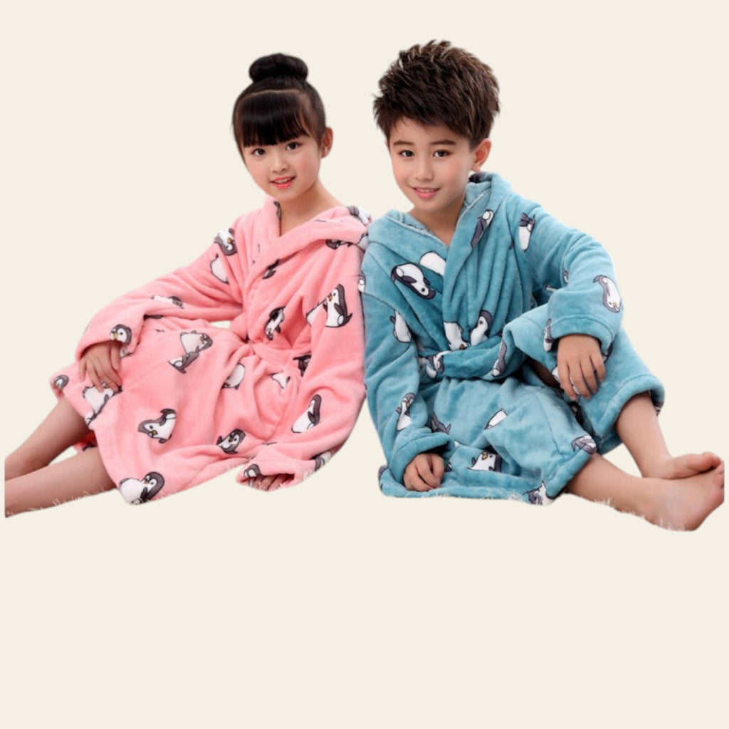 Two children wearing pink and blue bathrobes with animal patterns, sitting on a carpeted floor.