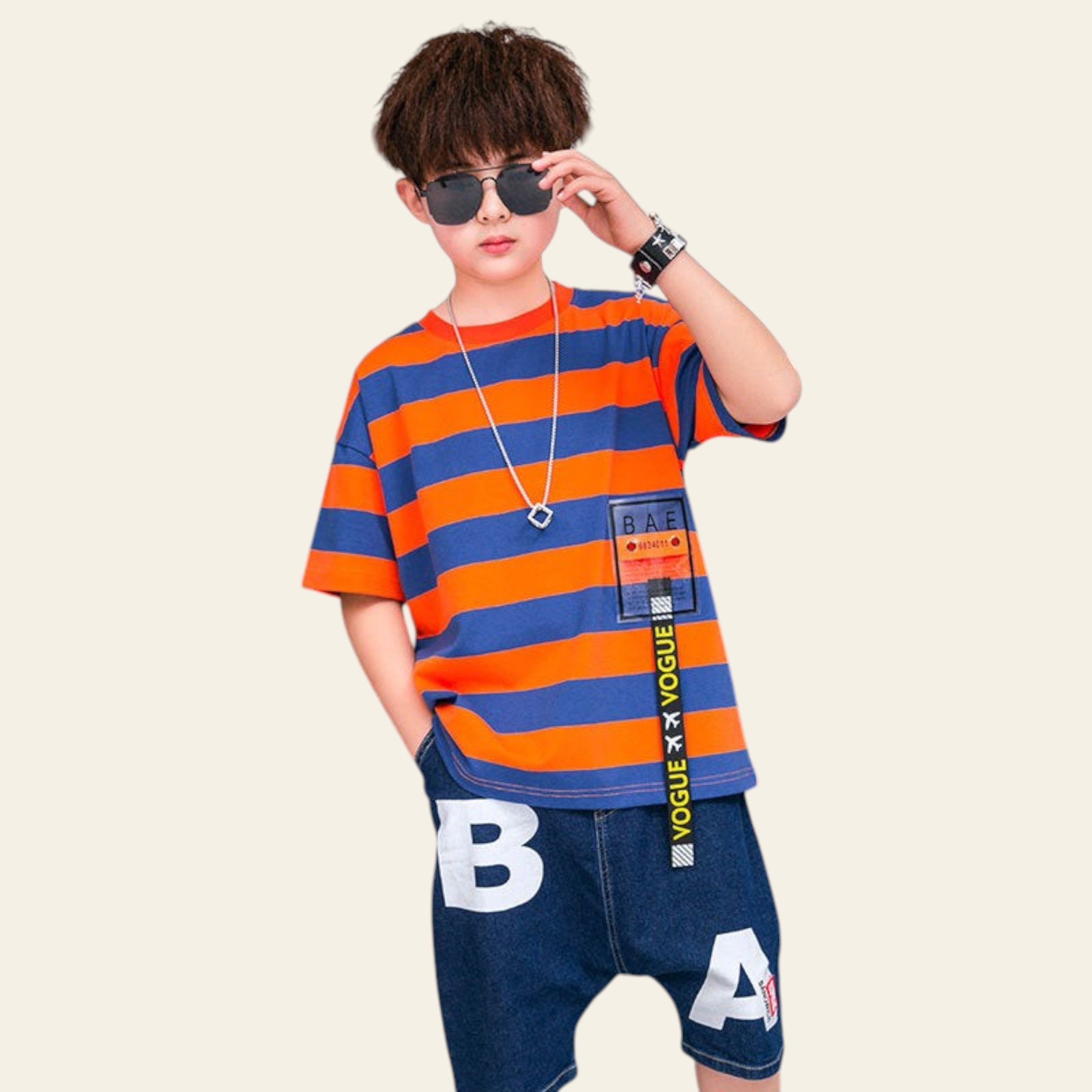 Child wearing an orange and blue striped shirt with a visible brand logo, standing in front of a branded backdrop.