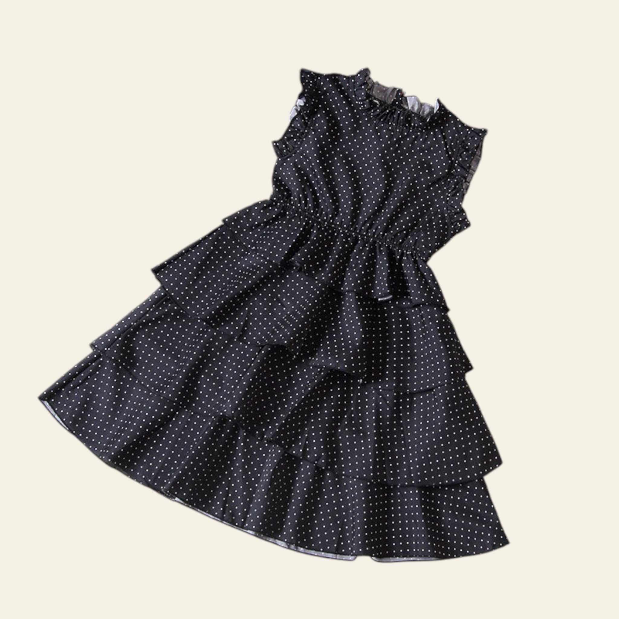 Black polka dot dress with ruffled layers on a beige background