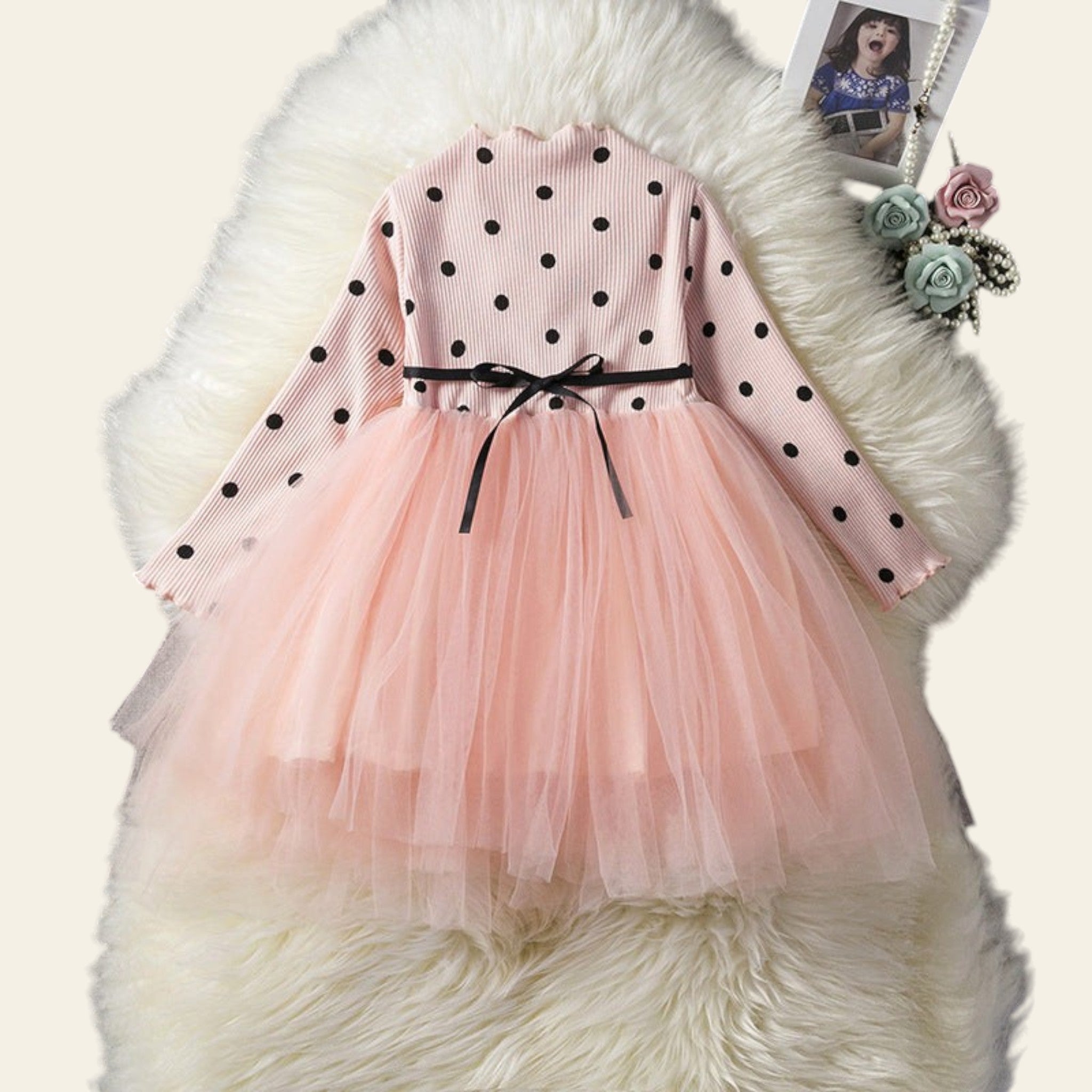 Pink dress with black polka dots on a fluffy white surface