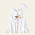 White lace dress with a gold bow and matching headband on a wooden surface.