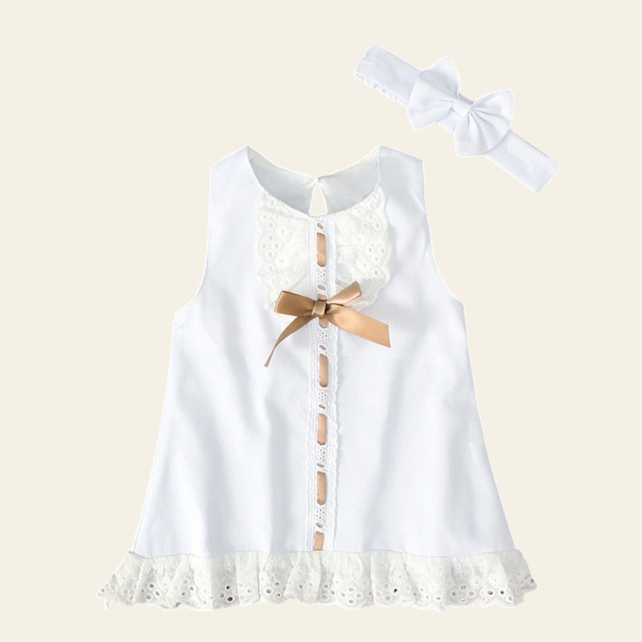 White lace dress with a gold bow and matching headband on a wooden surface.