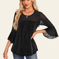 Woman wearing a black blouse with bell sleeves in an elegant interior setting
