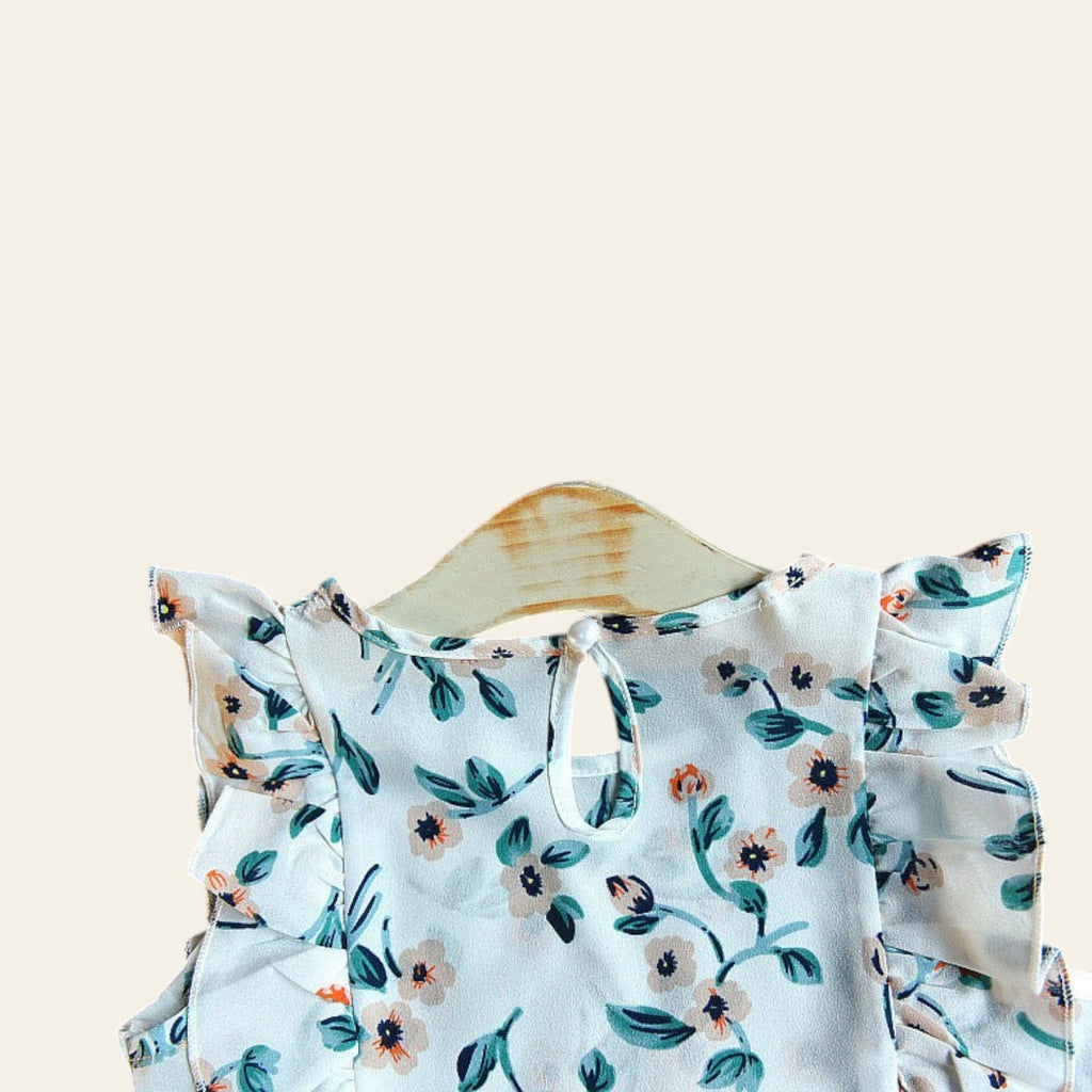 Floral-patterned top on a wooden hanger with flowers in the background