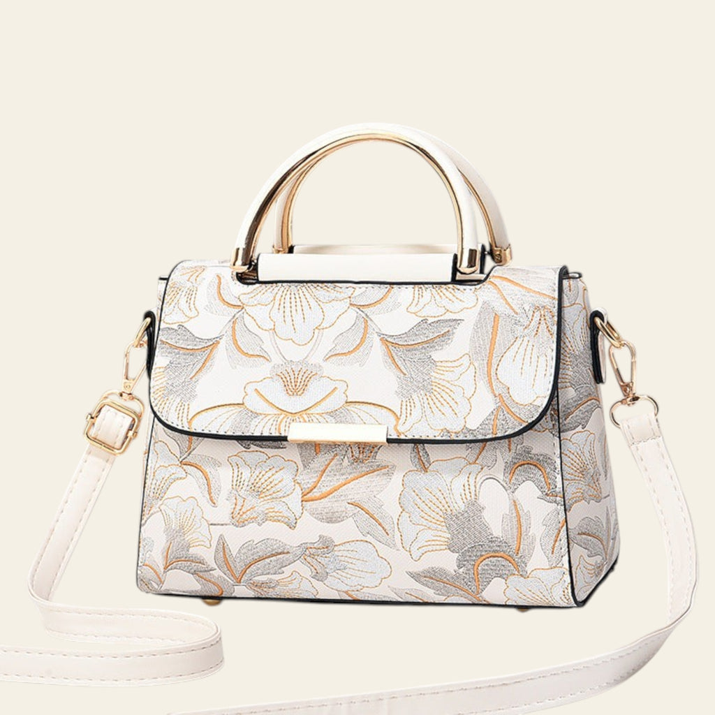 Floral patterned handbag with gold accents on a light gray background