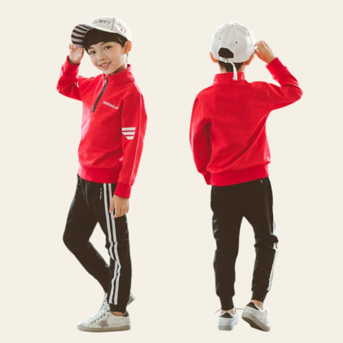Child wearing a red jacket and black pants with white stripes, standing against a plain background.