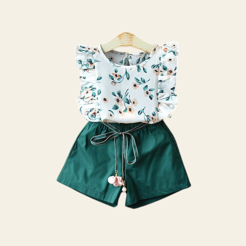 Children's outfit with floral top and green shorts on a gray background