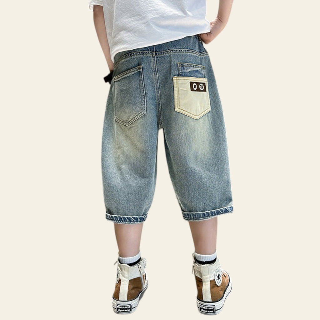 Person wearing light blue denim shorts with a white shirt and sneakers in a bathroom setting.
