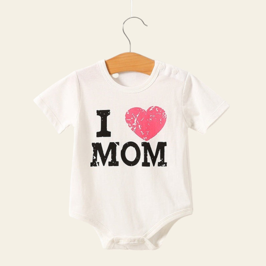 White baby onesie with 'I ❤️ MOM' text on a wooden hanger against a white background