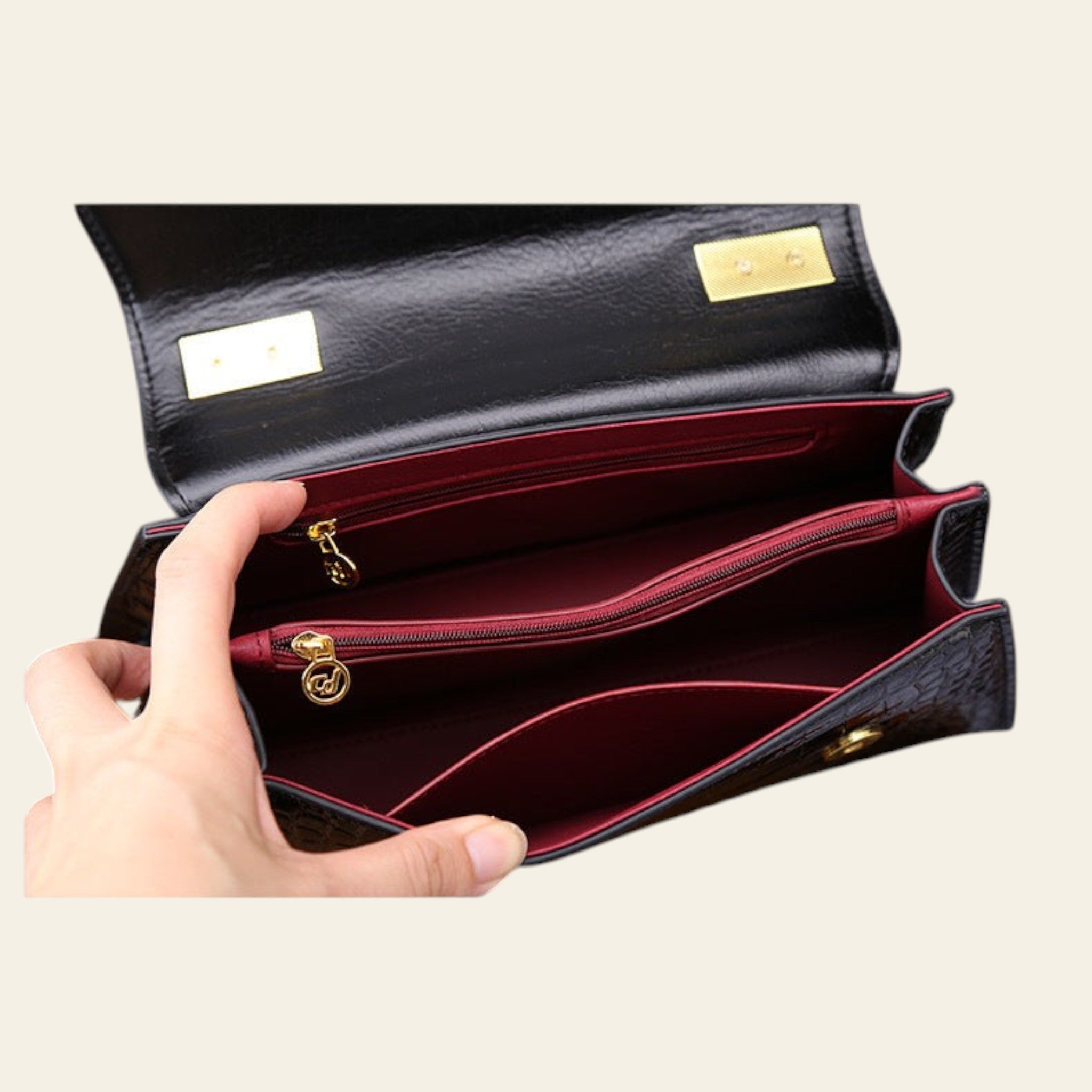 Black leather wallet with gold accents held open by a hand on a wooden surface.