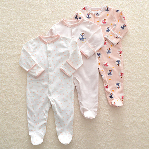 Three baby onesies with different patterns on a beige surface
