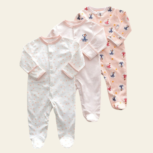 Three baby onesies with different patterns on a beige surface