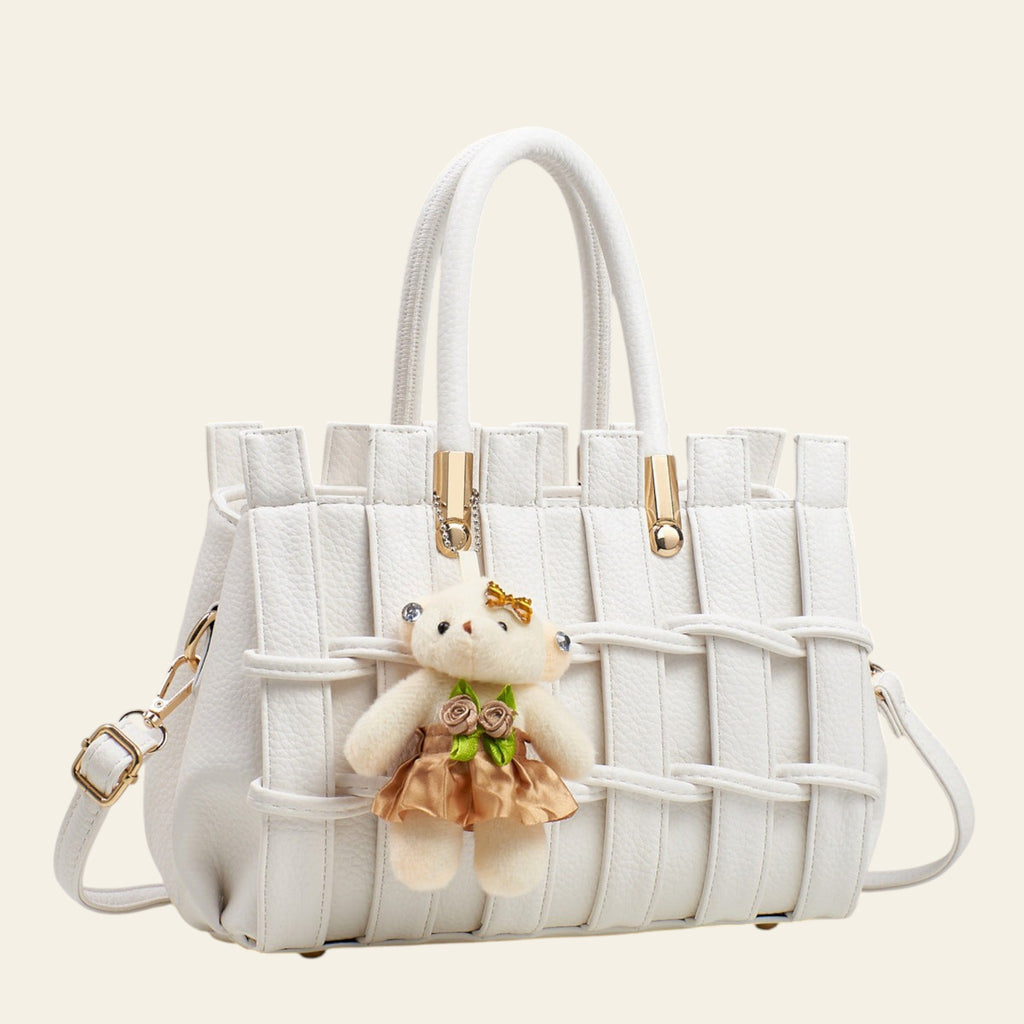 White woven handbag with a teddy bear keychain on a light gray background