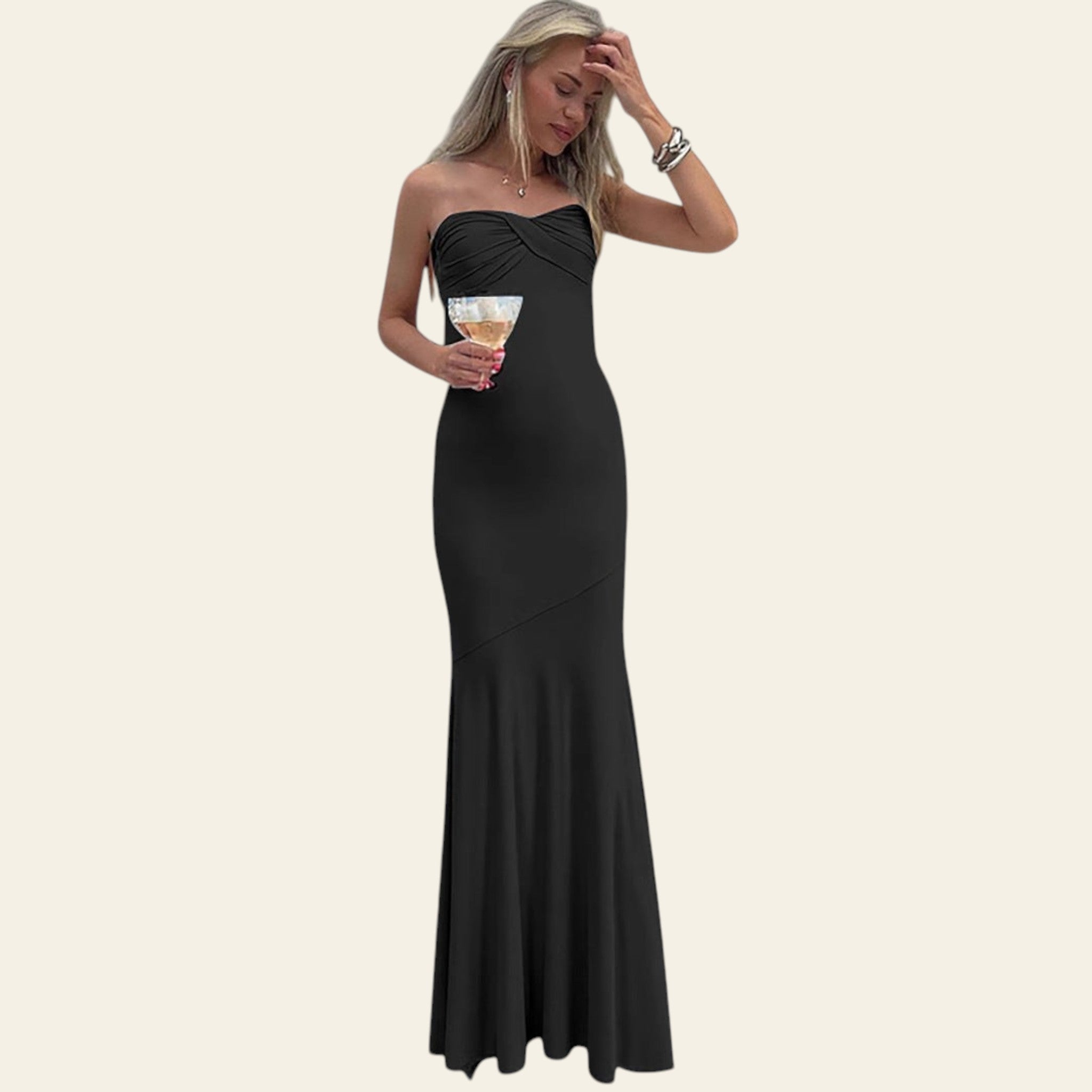 Woman in a black strapless gown standing on a staircase holding a glass.