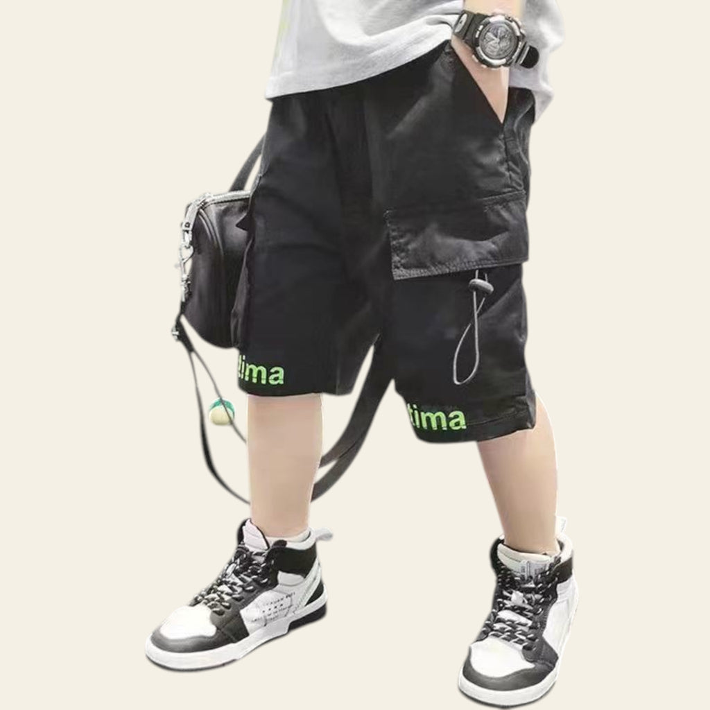 Person wearing black shorts with 'uma' branding, standing indoors.
