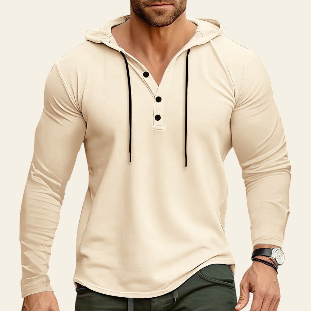 Man wearing a beige long-sleeve shirt with black buttons against a blurred background