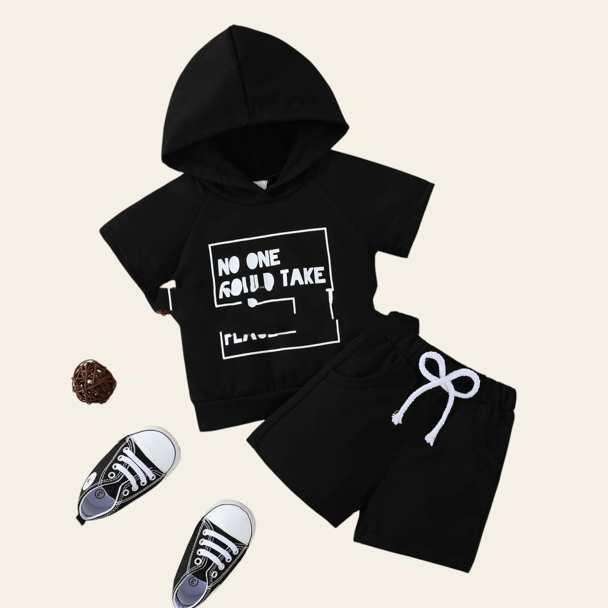 Black hoodie and shorts set with text on a wooden surface, accompanied by black sneakers.