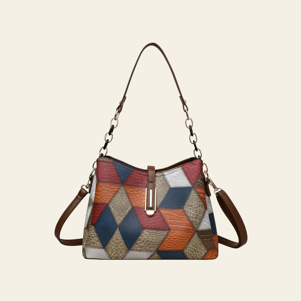 Multicolored patchwork handbag with brown leather accents on a white background