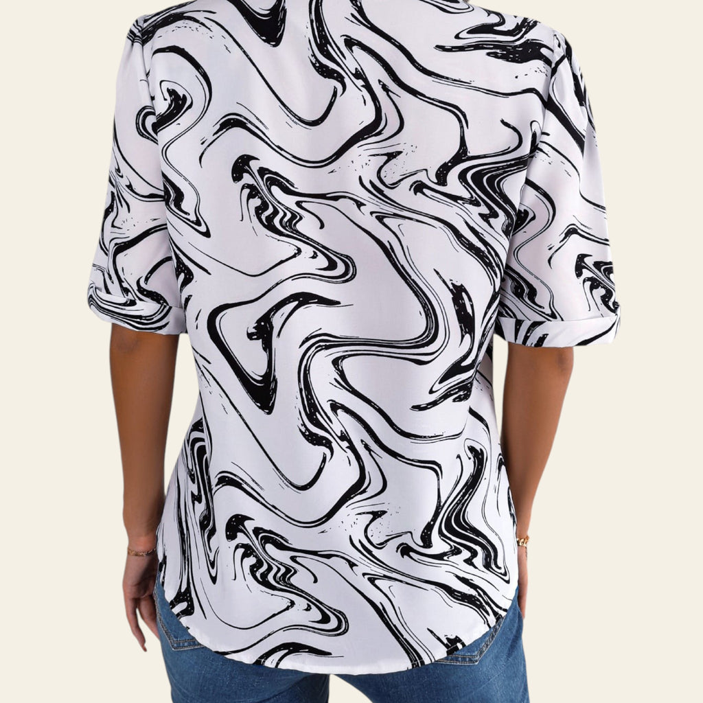 Person wearing a black and white abstract patterned shirt in a casual setting.