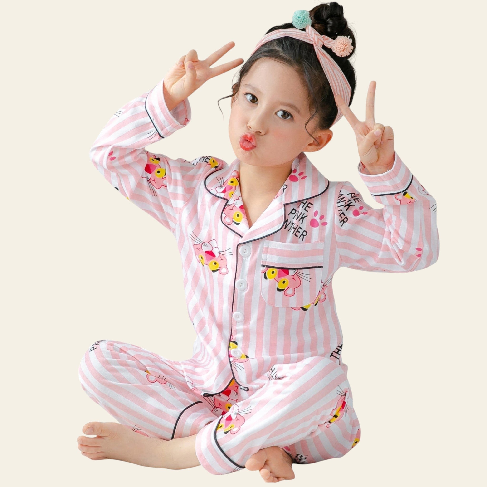 Child wearing pink striped pajamas with cartoon characters, making peace signs.