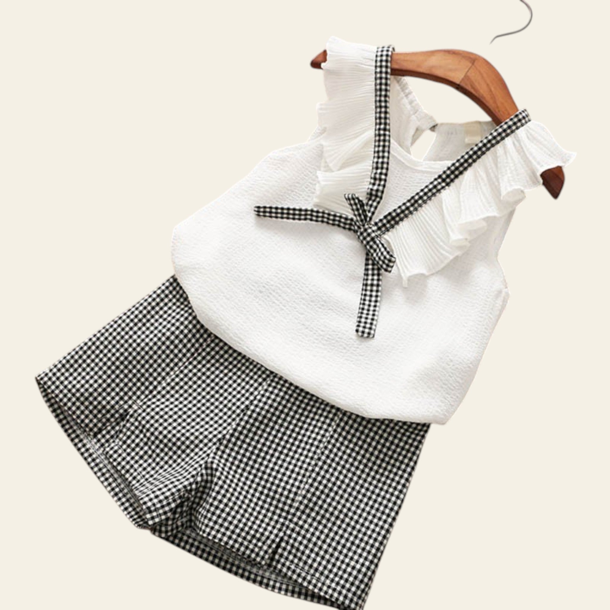 White top with ruffles and black checkered shorts on a wooden surface