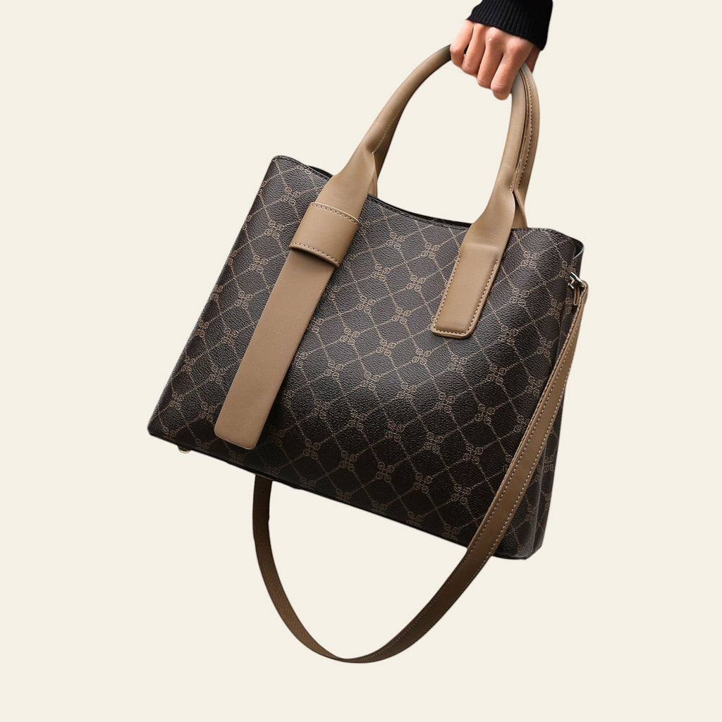 Person holding a patterned handbag with a neutral color scheme on a wooden floor.