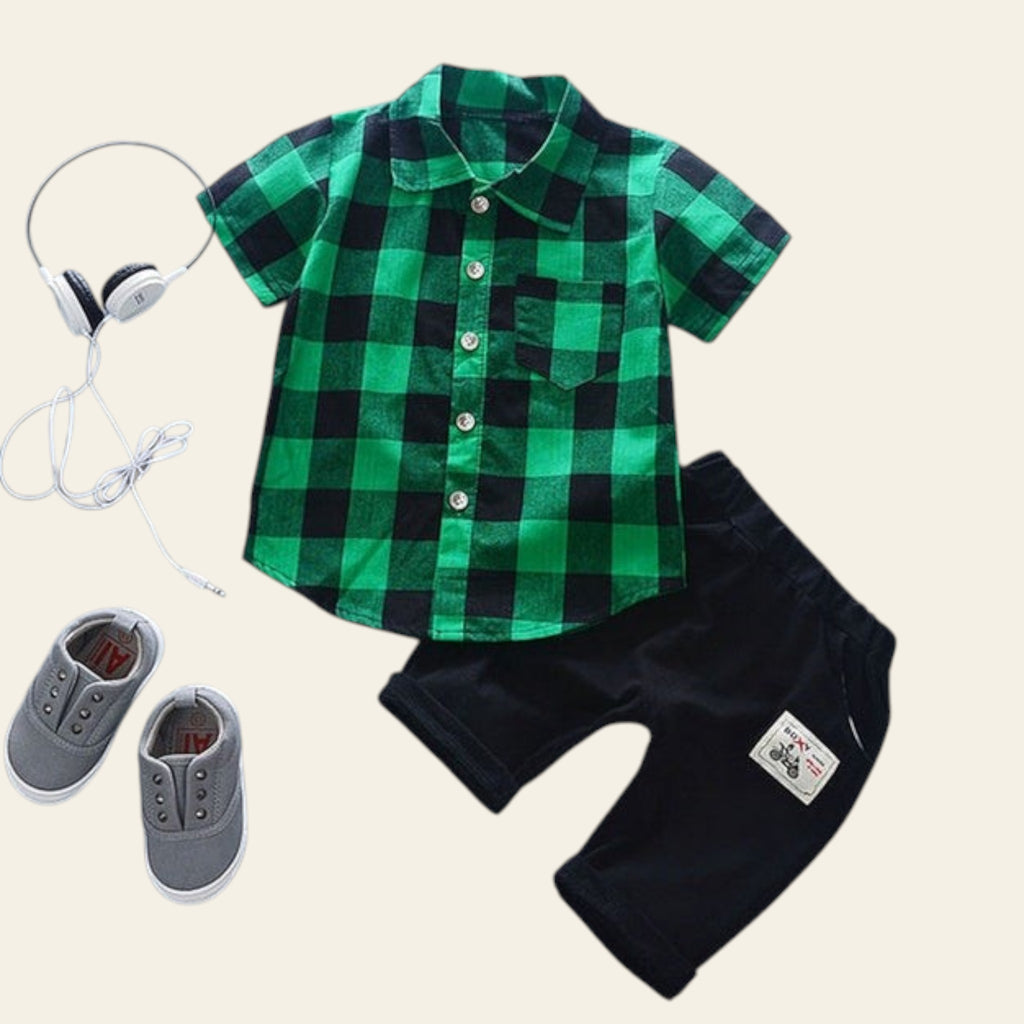 Green and black checkered shirt with black shorts, gray sneakers, and headphones on a light blue background