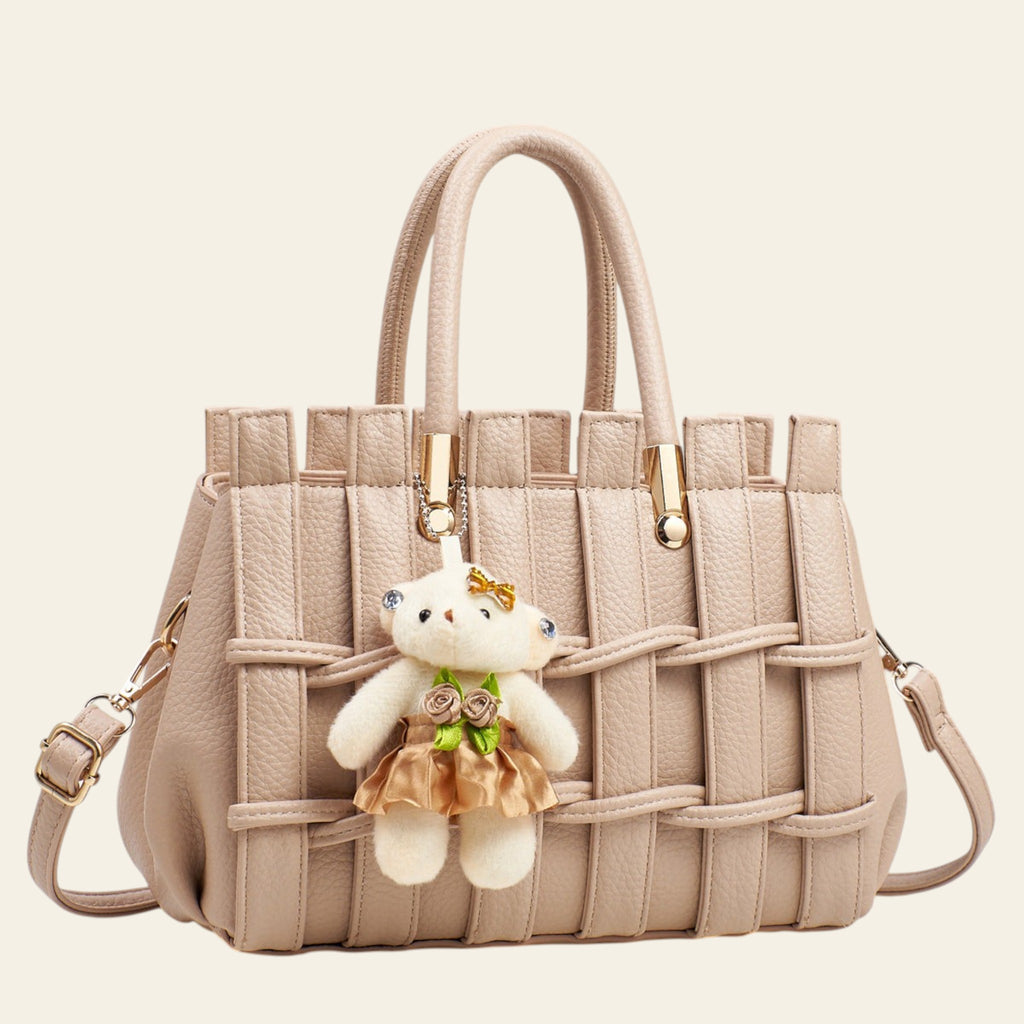 Beige woven handbag with a teddy bear charm on a light gray background