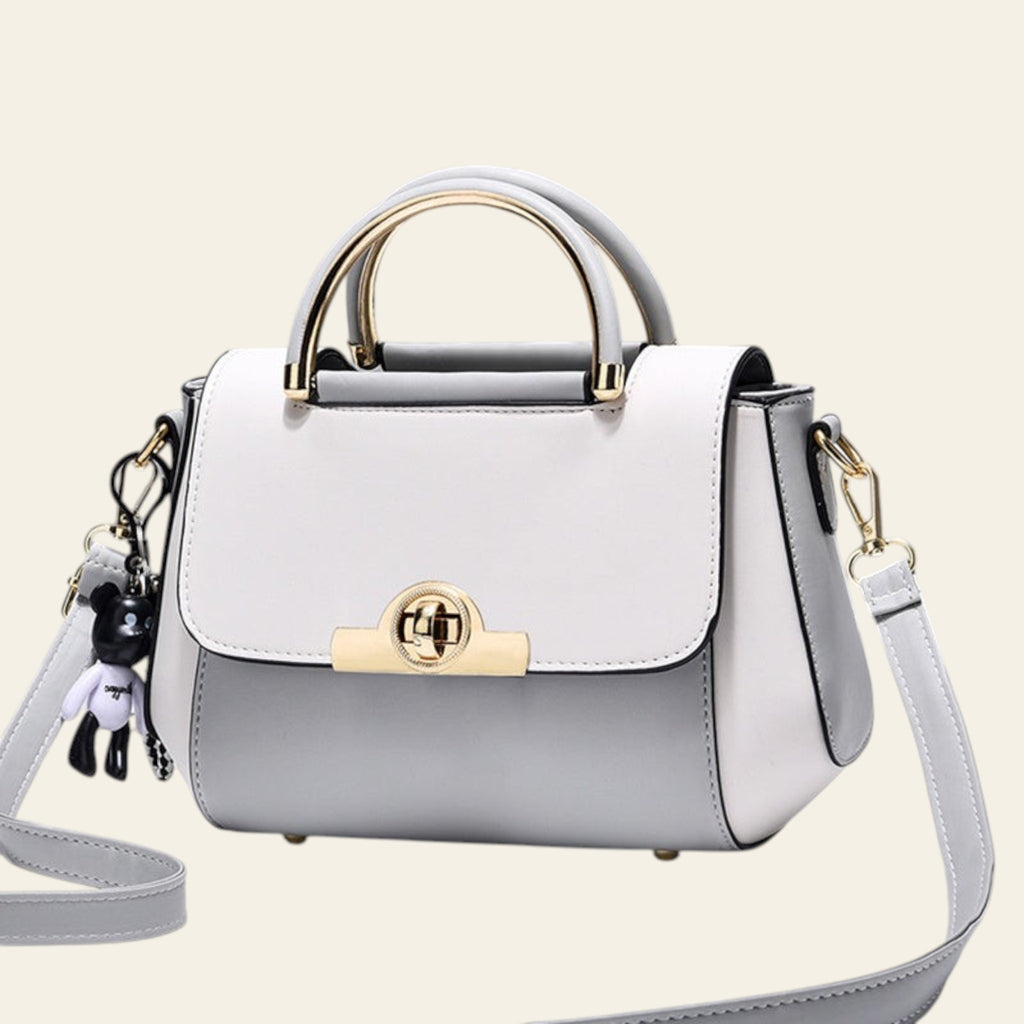 White handbag with gold accents on a light gray background
