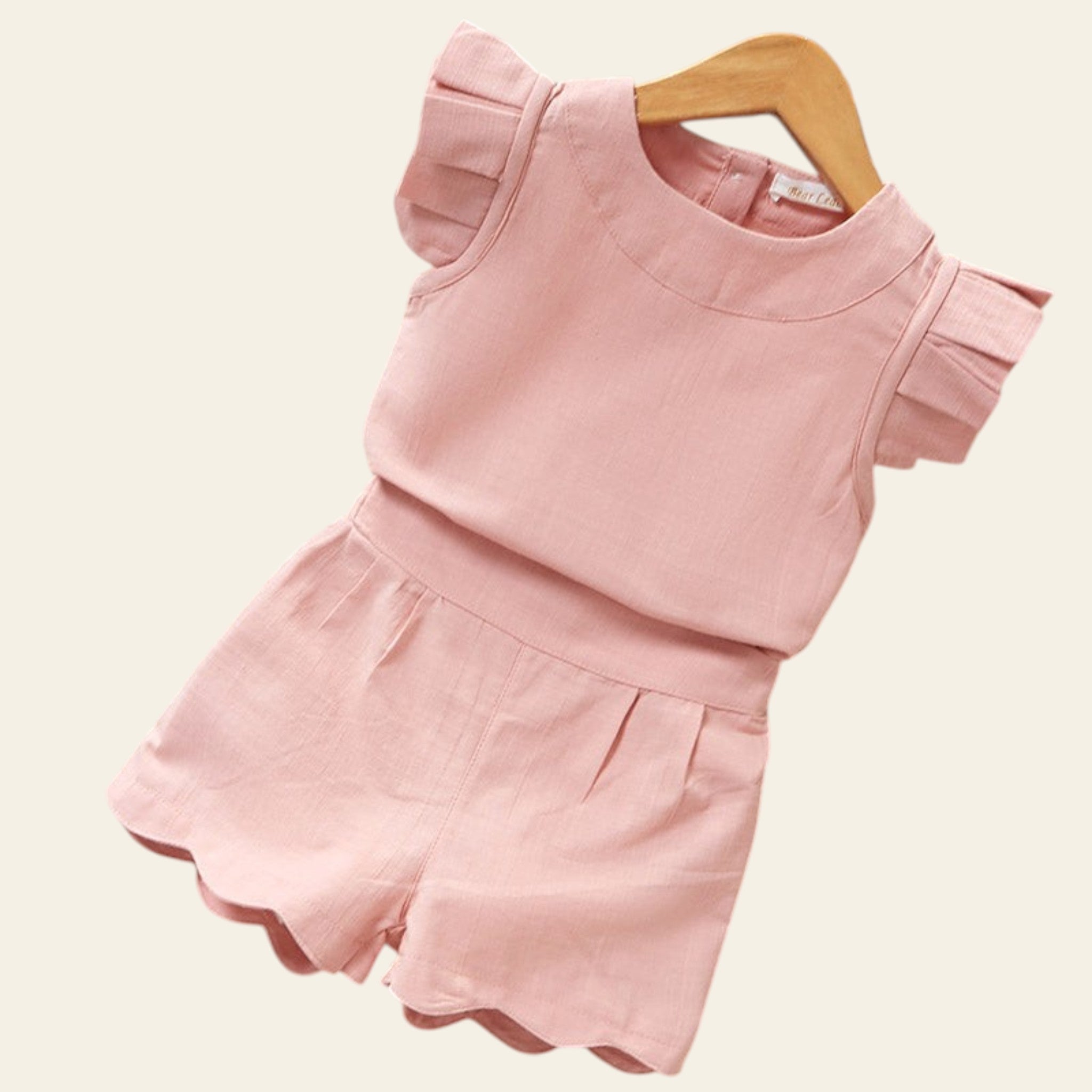 Pink children's outfit with ruffled sleeves on a wooden surface