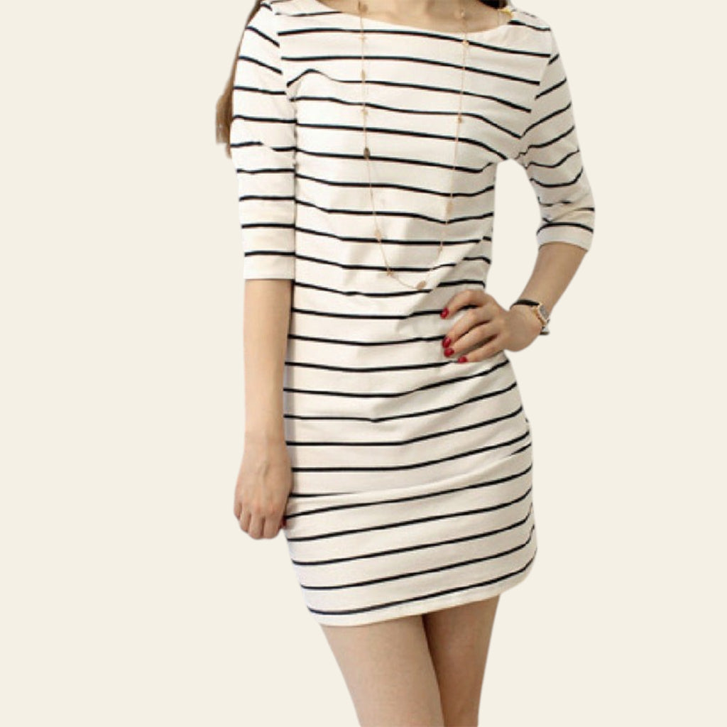 Person wearing a black and white striped dress in a room with a window and sofa.