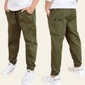 Two pairs of green pants worn by people on a wooden floor.