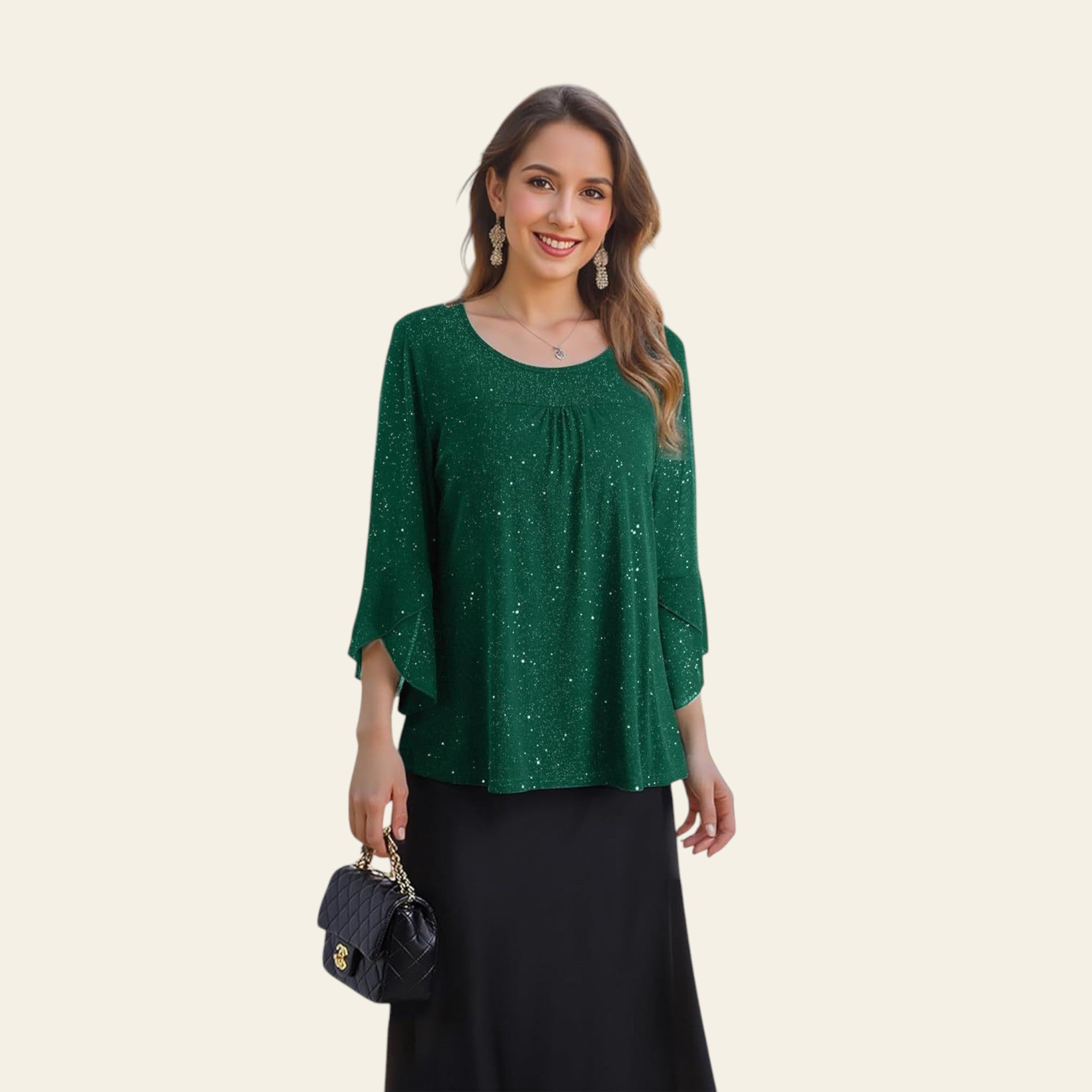 Woman in a green top and black skirt standing in front of floral decorations.