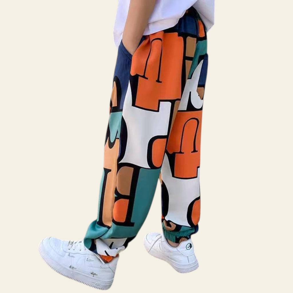 Person wearing colorful pants with abstract patterns and white sneakers outdoors.