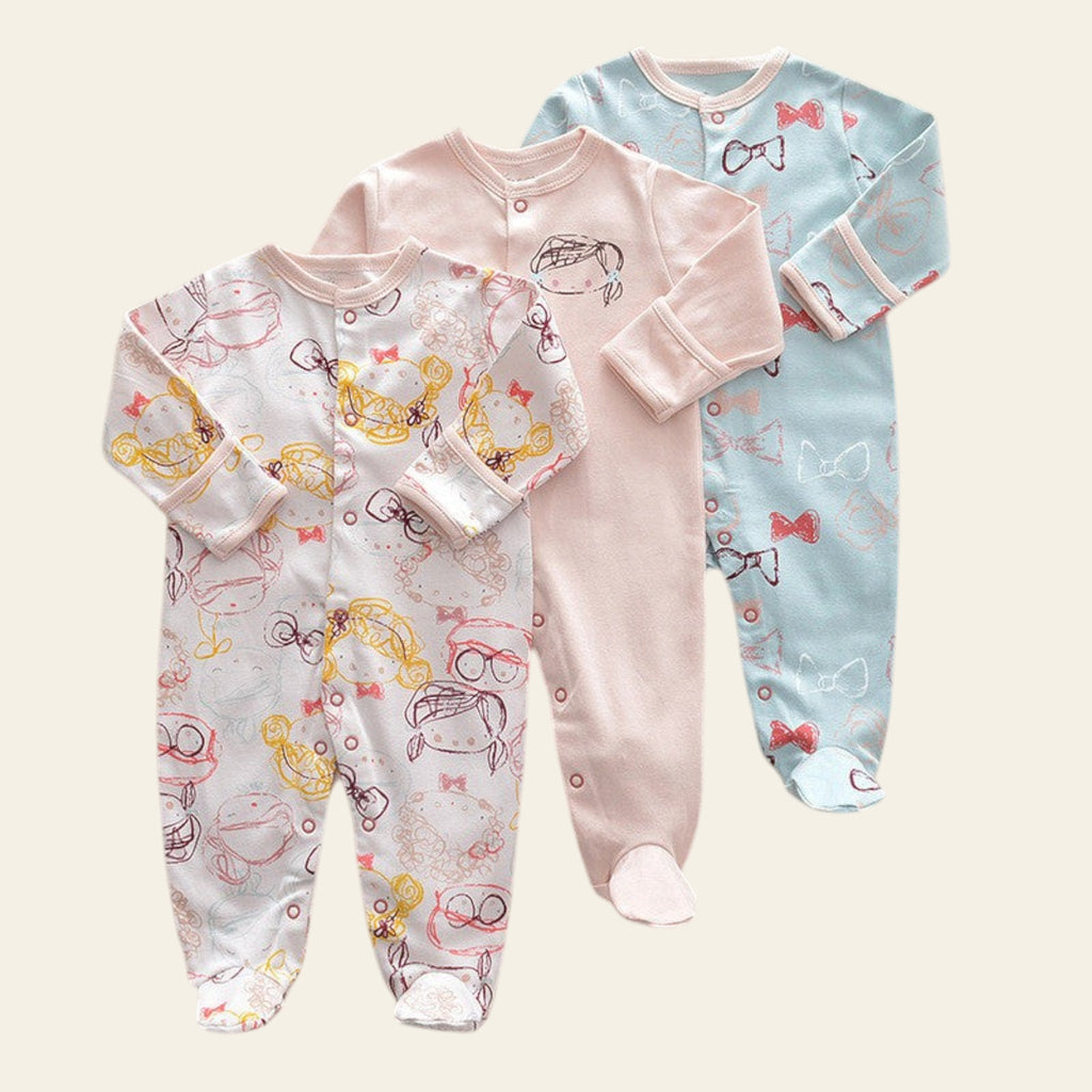 Three baby onesies with different patterns on a beige surface