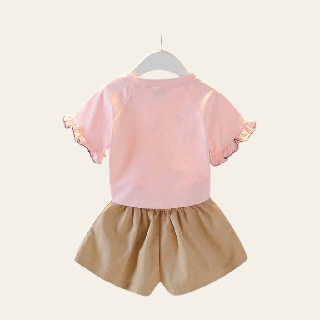 Children's pink top and beige shorts set on a hanger against a gray background.