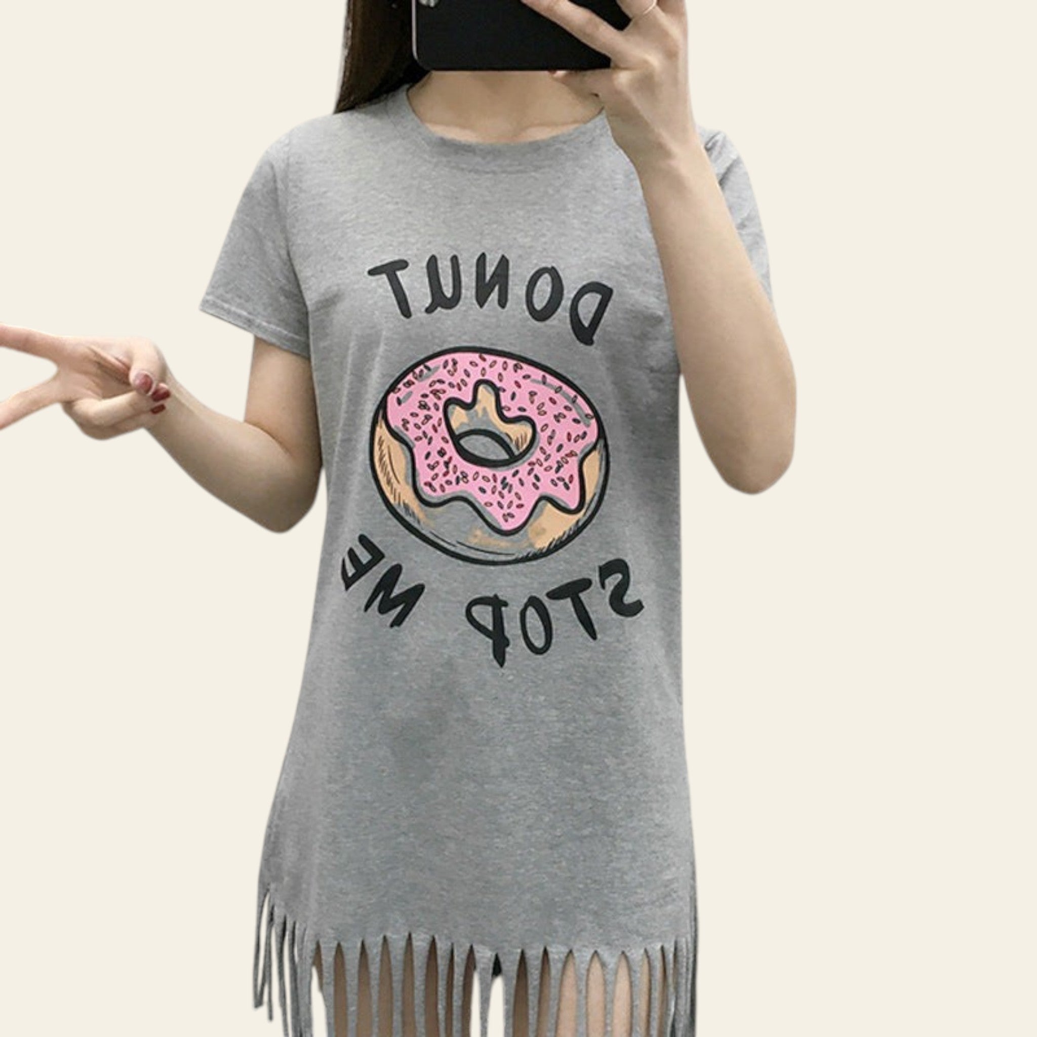 Person wearing a gray t-shirt with a donut graphic and text, standing against a white brick wall.