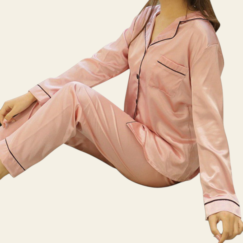 Pink satin pajama set with black piping on a white background