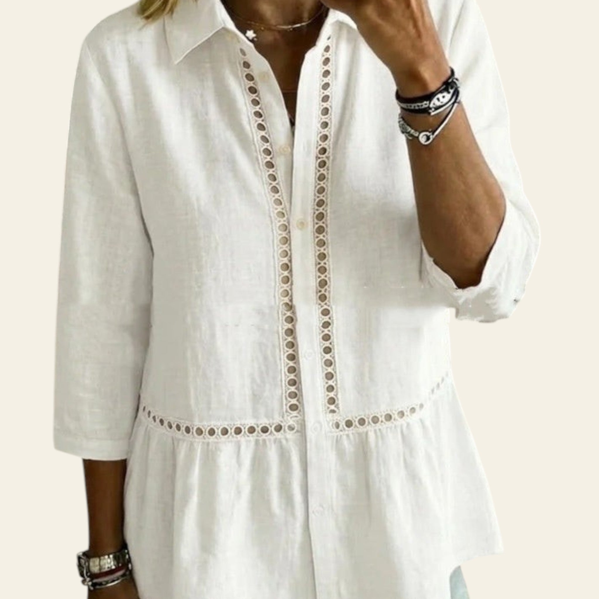 Person wearing a white blouse with intricate detailing in a home setting