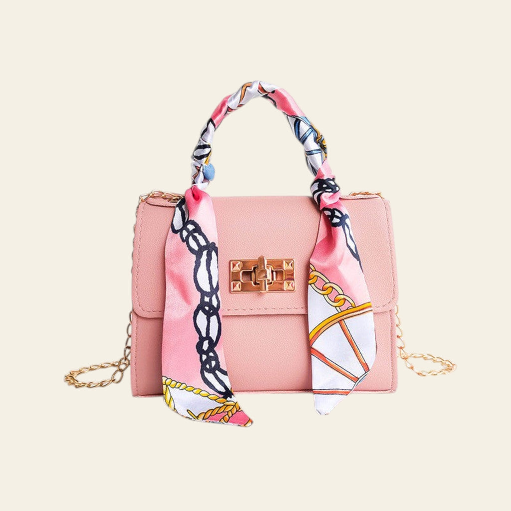 Pink handbag with a colorful scarf draped over it on a white background